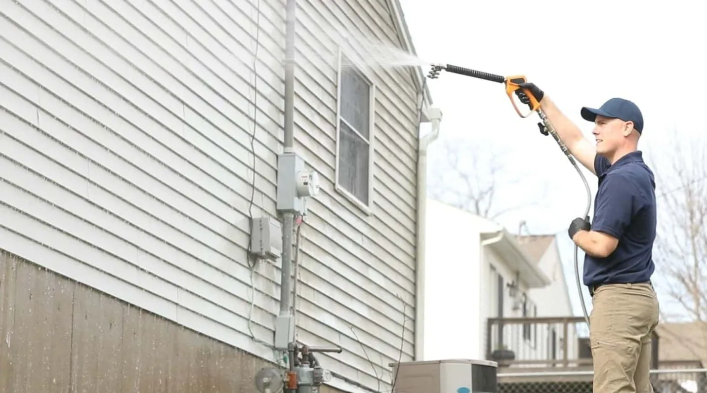 Property Power Wash technician soft-washing the siding of a Southeast Michigan home